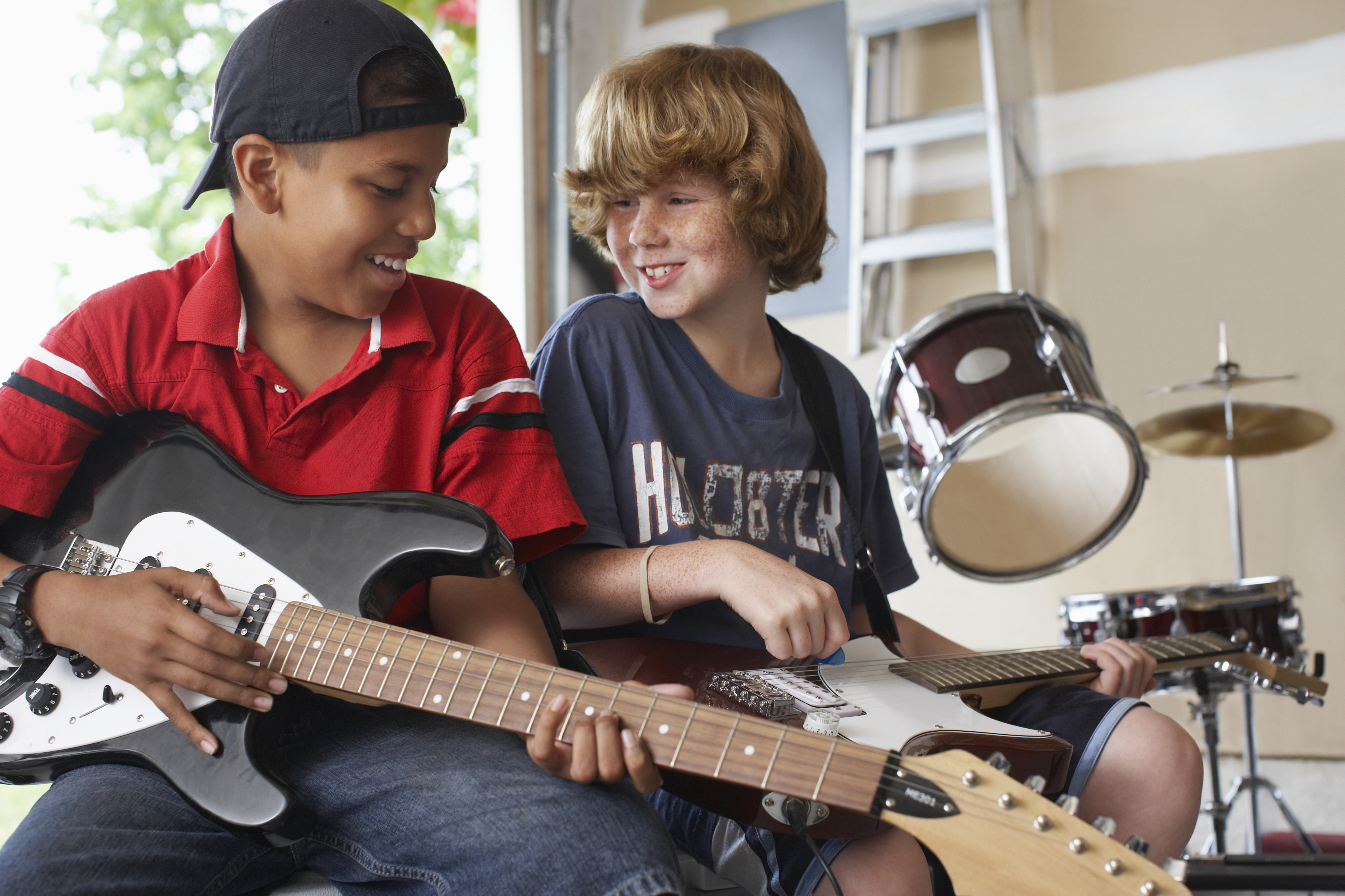 Two young teens learning to play guitar and drums