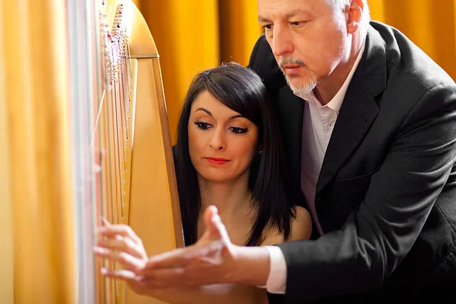 A woman being taught how to play a harp